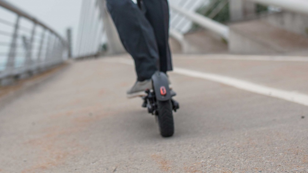 person åker elektrisk scooter på bro